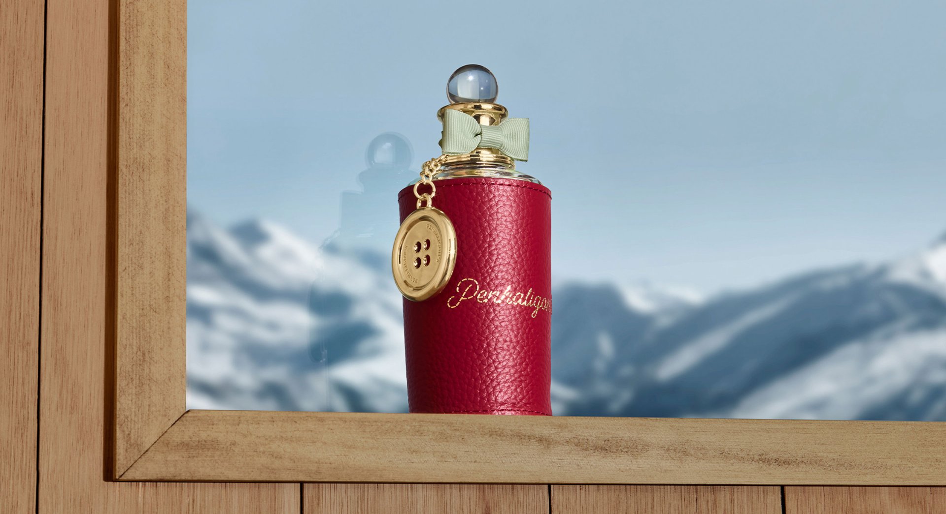 Halfeti bottle on ski lodge window sill with red leather sleeve, gold monogramming and gold button charm