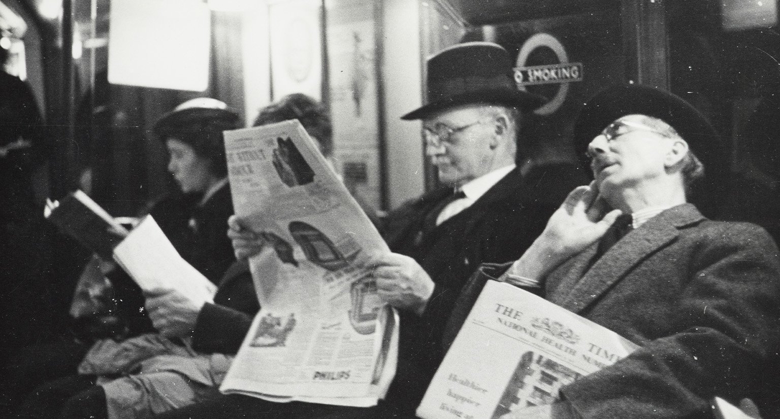 Men reading newspaper inside tube train