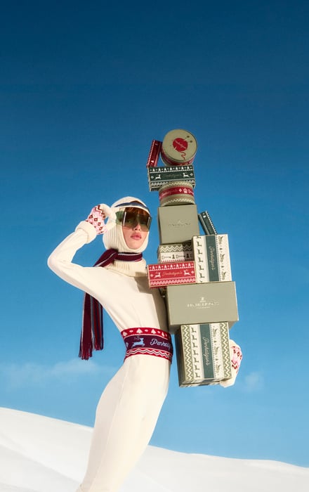 Woman in ski suit holding penhaligons Christmas gift boxes