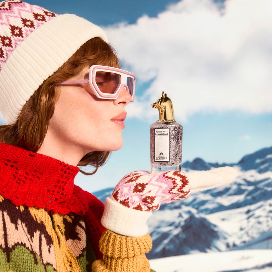 Woman blowing ice off Duchess Rose bottle in ski alps